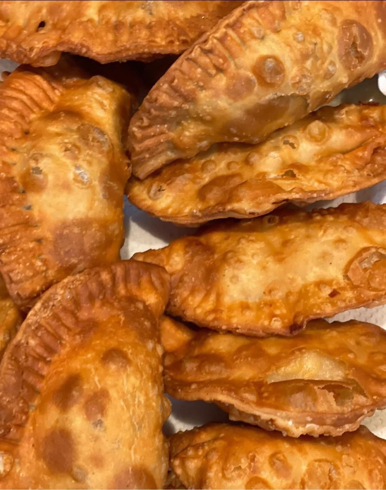 Overhead close-up of crimped KDM empanadas with blistered, crispy crust